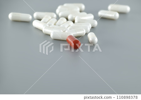 Medical capsule pills scattered on gray surface 110898378
