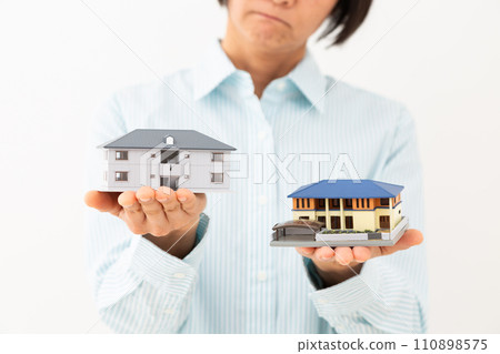 一位中年婦女擔心手上拿著獨立屋和公寓的模型。 110898575