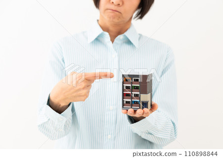 一位中年婦人拿著公寓大樓的模型,憂心忡忡。 一位中年婦人拿著公寓大樓的模型,憂心忡忡。 110898844