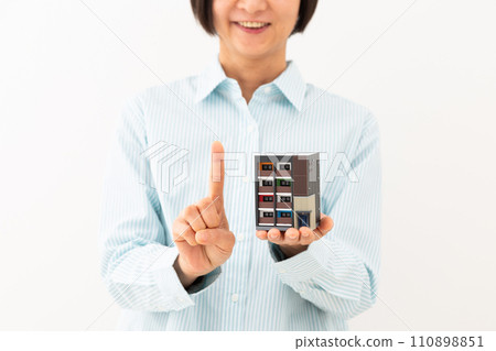 一位中年婦女拿著公寓大樓模型，微笑著舉起食指 110898851