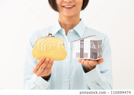 A smiling woman holding a wallet and a house model 110899474