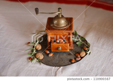 Retro coffee grinder on table with nuts and olive branch over beautiful old linen tablecloth 110900387