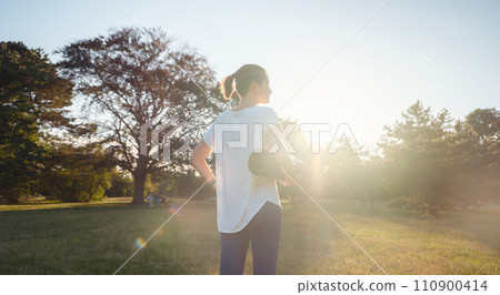 Healthy active lifestyle concept in city park. woman walking with exercise mat through park in summer day, after or before health fitness, wellness exercise or outdoor workout. 110900414