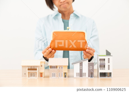 A woman who is worried about her wallet and multiple house models 110900625