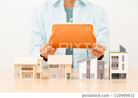 Middle-aged woman holding a wallet and multiple house models Middle-aged woman holding a wallet and multiple house models 110900632