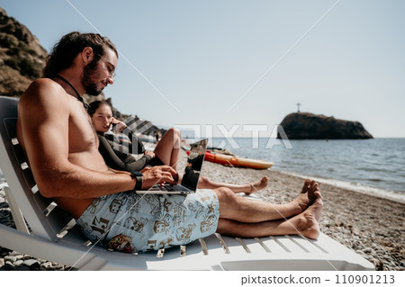 Man woman laptop sea. Working remotely on seashore. Happy successful couple, freelancers working on sea beach, relieves stress from work to restore life balance. Freelance, remote work on vacation Man woman laptop sea. Working remotely on seashore. Happy successful couple, freelancers working on sea beach, relieves stress from work to restore life balance. Freelance, remote work on vacation 110901213
