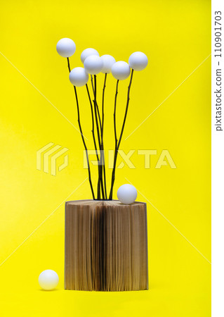 Still life with a book and a bouquet of white balls 110901703