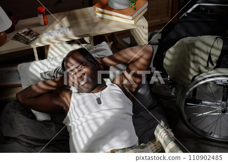 Sleepless african american man lying alone in his bedroom and looking out window 110902485