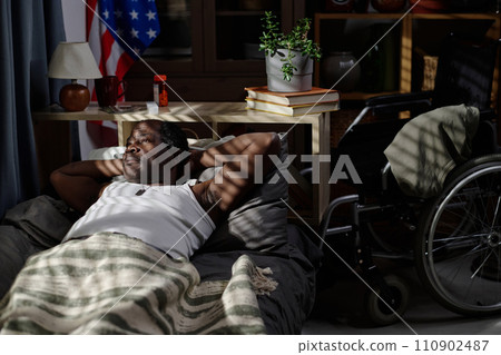 Mature african american man lying alone in his bed at night and thoughtfully looking out window Mature african american man lying alone in his bed at night and thoughtfully looking out window 110902487