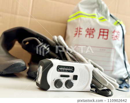Emergency bag, flashlight with radio, gloves and boots_cardboard background Emergency bag, flashlight with radio, gloves and boots_cardboard background 110902642