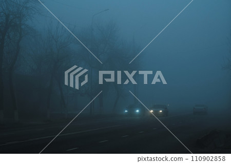 road with cars in city on a foggy morning in autumn in fog mist 110902858