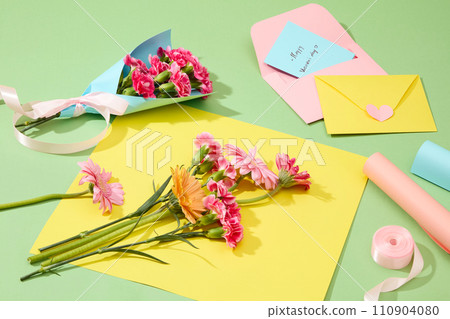 Creative ideas for women day decoration, fresh gerbera and carnation flowers with handmade paper envelopes on green background. Copy space 110904080