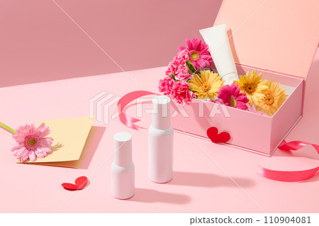 Happy Mother Day or Women day background with gift box full of decorative fresh flowers and empty cosmetic bottles on pink wallpaper. Mockup bottle unbranded for design 110904081