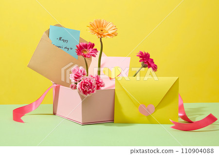 Front view of pink gift box fill with fresh flowers and cute paper cards for women on International Women Day. Minimalist concept for celebration. Blank space for design Front view of pink gift box fill with fresh flowers and cute paper cards for women on International Women Day. Minimalist concept for celebration. Blank space for design 110904088
