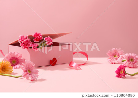 Cute pink background with gerberas and fresh carnations decorated. Sweet and romantic women day decoration ideas. Empty space for product presentation, front view 110904090