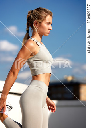 A young woman is training on the street, doing a warm-up, functional training, muscle stretching, cheerful, positive, in an urban environment. A young woman is training on the street, doing a warm-up, functional training, muscle stretching, cheerful, positive, in an urban environment. 110904527