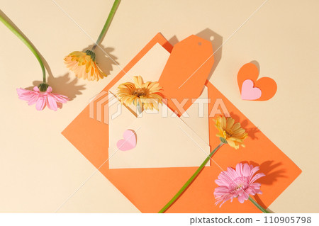 Colorful fresh flowers decorated with an opened envelope a piece of orange paper inside. Beige background. International Women Day is a day when women are recognized for their achievements Colorful fresh flowers decorated with an opened envelope a piece of orange paper inside. Beige background. International Women Day is a day when women are recognized for their achievements 110905798