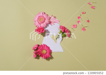 A woman made of paper decorated against pastel background with a lot of flowers and petals. The flowers are arranged as if the woman is holding a bouquet and the petals are flying A woman made of paper decorated against pastel background with a lot of flowers and petals. The flowers are arranged as if the woman is holding a bouquet and the petals are flying 110905852