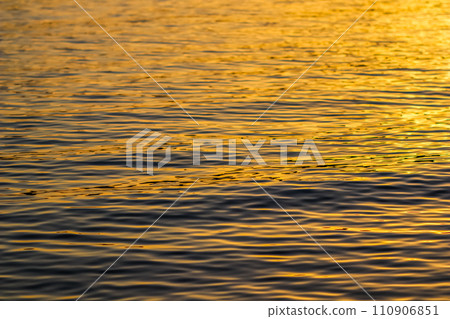 Golden sea waves in sunset glow as surface background. Summer holidays and coastal nature concept 110906851