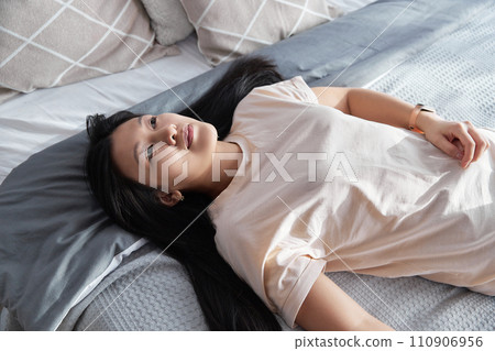 Happy asian woman in casual clothes lying on the bed at home 110906956