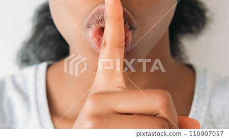 Shush gesture. Secret sign. Unrecognizable cropped portrait of quiet speechless woman with finger at lips in silence symbol on light background. 110907057
