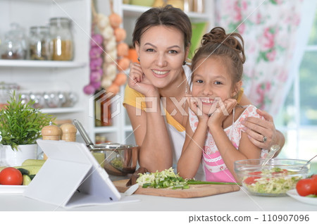 Portrait of mother and daughter cooking together 110907096