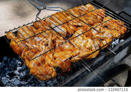 BBQ picnic time Roasted chicken legs and wings on grill. Grilling meat on outdoor grill grid tasty barbeque chicken steak with smoke flames juicy meat in the backyard 110907118