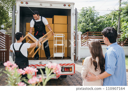 Moving house made easy for a couple with the help of a professional delivery team. They work together unloading and lifting cardboard boxes for efficient relocation. Moving Day Concept 110907164