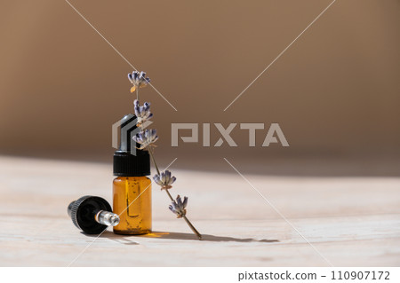 Glass bottle dropper with dried lavender flowers. Wild harvested essential oil beauty product. Organic herbs skincare ingredient environmentally friendly Glass bottle dropper with dried lavender flowers. Wild harvested essential oil beauty product. Organic herbs skincare ingredient environmentally friendly 110907172