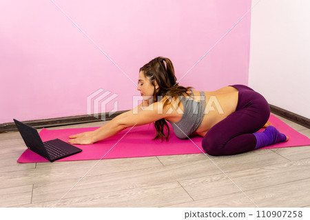 Woman in comfortable maternity wear, focused on an online fitness class 110907258