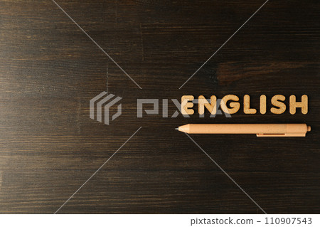 The word "English" and a notebook, the concept of learning English, on a dark background. 110907543