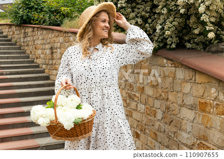 Beautiful girl with flowers on the street in summer. 110907655