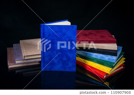 Different colour notebooks on a black background Different colour notebooks on a black background 110907908