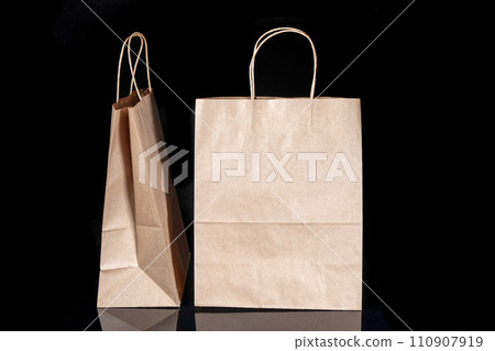 Recyclable craft paper bag for purchases, gifts and takeaway food mock up on black background. Environmentally friendly than single-use plastic bags 110907919