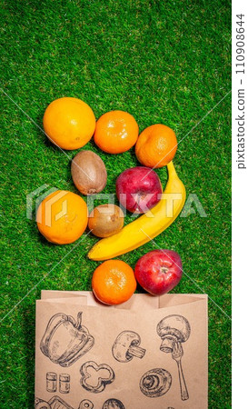 Banana, red apple and different fruits with craft paper bag laying on grass, flat lay. Space for text. Zero waste concept. 110908644