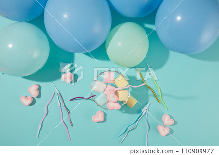 Marshmallow candy and colored candles are decorated on a blue background with balloons. Birthday theme with pastel colors. Copy space with top view. 110909977
