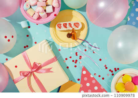 Balloons are decorated around the frame. A gift box, a plate of marshmallows, a plate of macarons and a plate of cakes are displayed on a blue background with confetti. 110909978