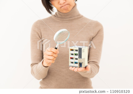 一名中年婦女拿著公寓模型和放大鏡，憂心忡忡。 110910320