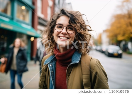 Portrait of a happy young woman in the city, wearing glasses. 110910976