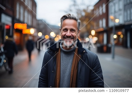 Portrait of a handsome middle-aged man smiling at the camera in the city. 110910977