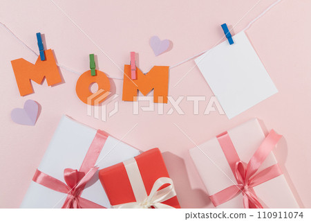 Gift boxes, MOM letters, paper hearts and blank cards are displayed on a pastel background. Space for writing wishes to mother on women day or mother day. Gift boxes, MOM letters, paper hearts and blank cards are displayed on a pastel background. Space for writing wishes to mother on women day or mother day. 110911074