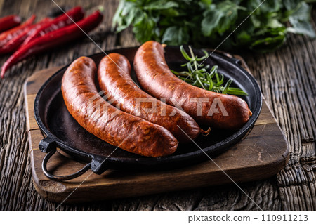 Pepper pork smoked sausages with rosemary in a cast iron pan Pepper pork smoked sausages with rosemary in a cast iron pan 110911213