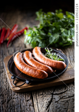 Pepper pork smoked sausages with rosemary in a cast iron pan Pepper pork smoked sausages with rosemary in a cast iron pan 110911214