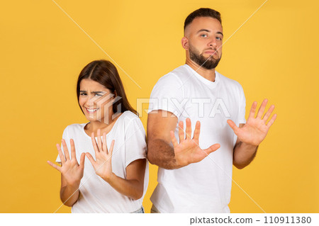 Unhappy displeased young european couple in white t-shirts make stop gesture with hands Unhappy displeased young european couple in white t-shirts make stop gesture with hands 110911380