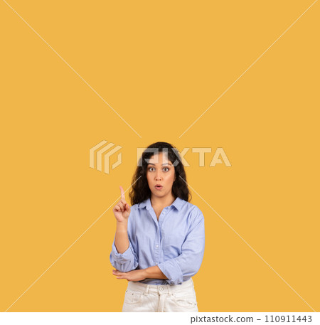 Shocked latin millennial brunette woman in casual point finger at copy space 110911443