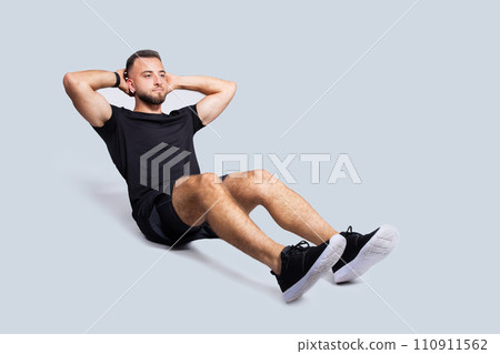 Focused handsome strong young caucasian man with beard in sportswear make exercises for abs Focused handsome strong young caucasian man with beard in sportswear make exercises for abs 110911562