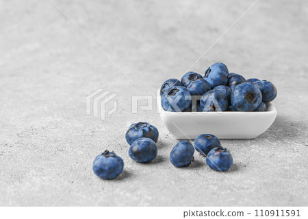 Fresh blueberries in a small square bowl on gray concrete background with copy space Fresh blueberries in a small square bowl on gray concrete background with copy space 110911591