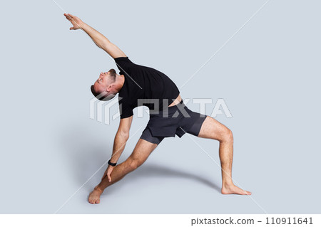 Calm young caucasian man with beard in sportswear practice yoga, stretching body Calm young caucasian man with beard in sportswear practice yoga, stretching body 110911641