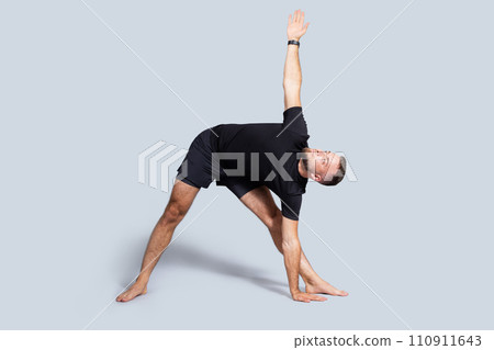 Calm handsome millennial european guy with beard in sportswear practice yoga, breath exercises, stretching body 110911643
