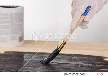painting wooden background, hand with brush and can of paint 110911778